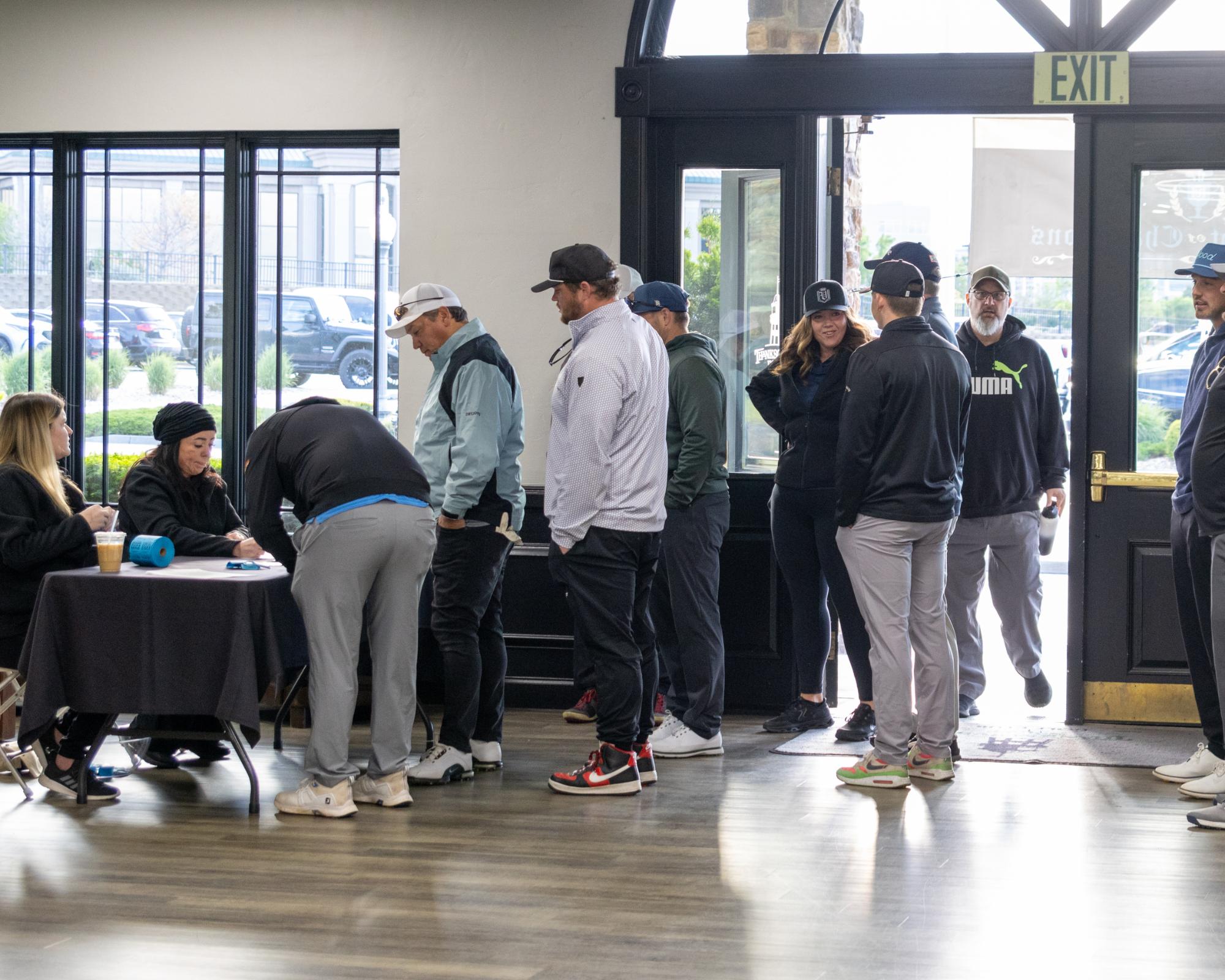 Line of participants signing in at the registration desk inside the clubhouse lobby