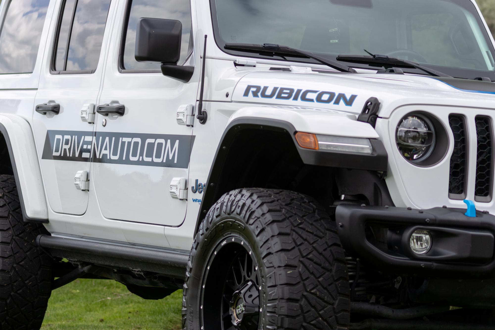 White Jeep Rubicon parked on the course with a DrivenAuto.com logo on its door as an event vehicle sponsor